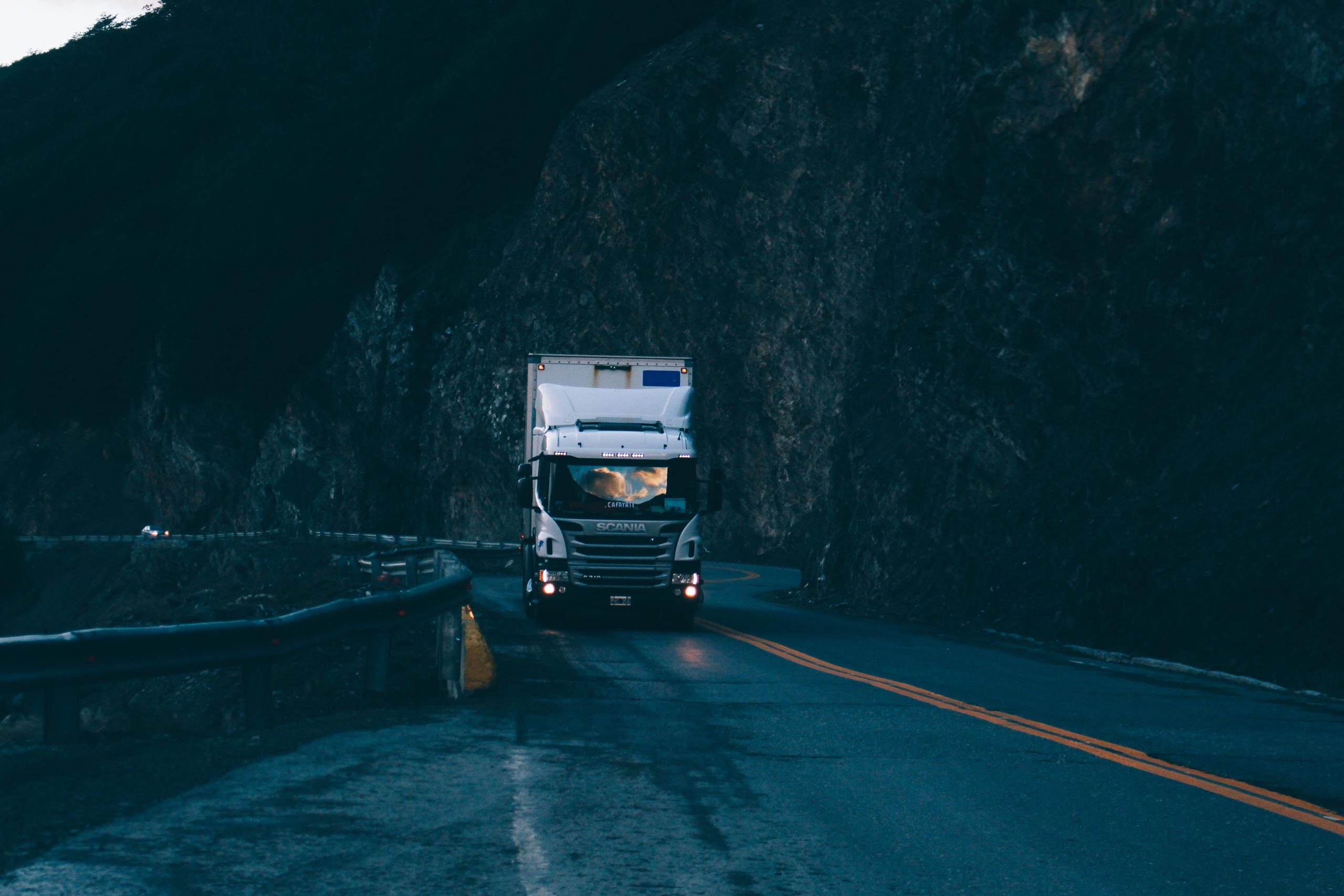 truck driving on a dark and rainy highway